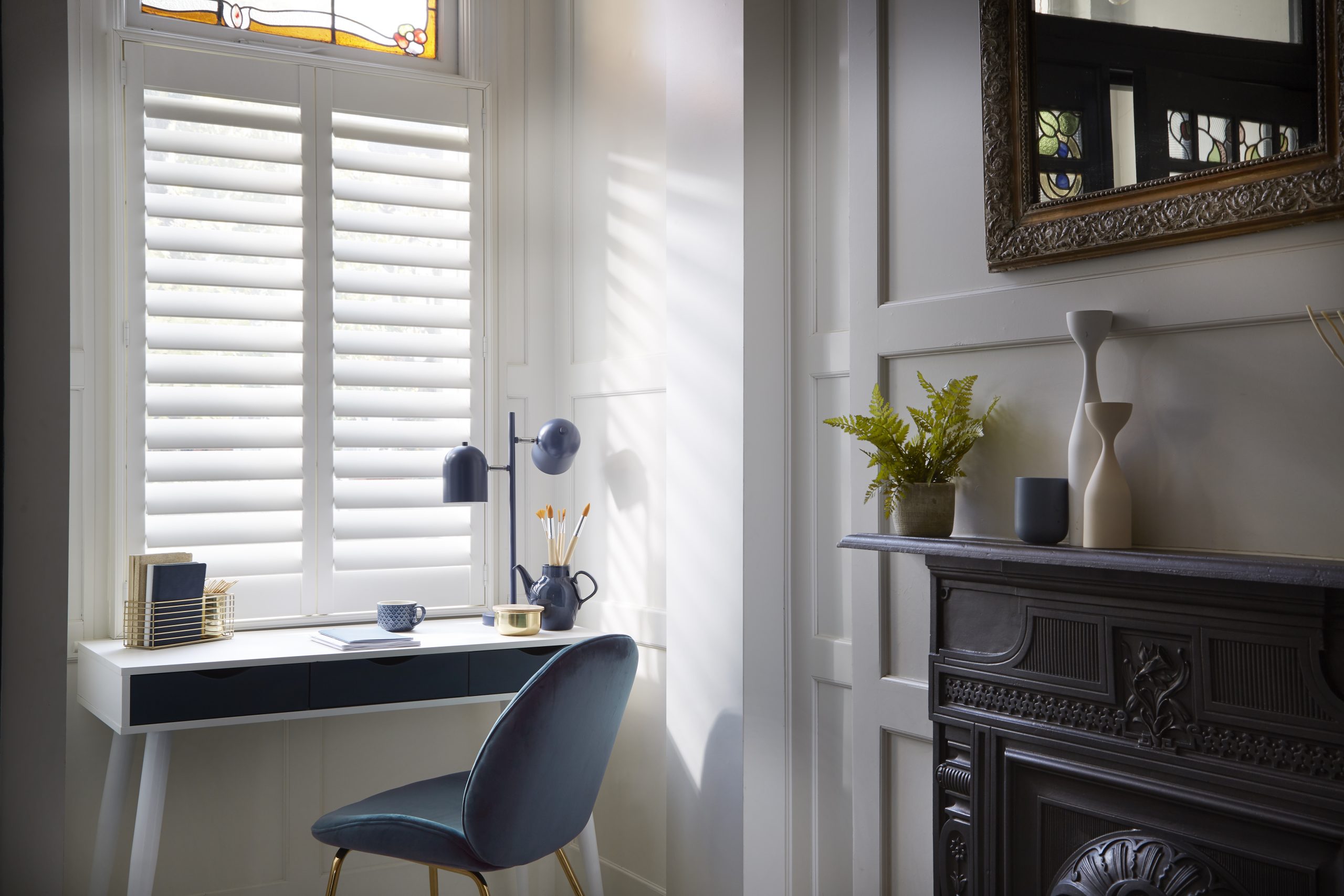 Exclusive Shutters Range at window with desk and chair, with a fireplace and mirror